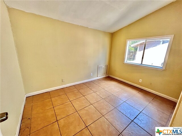 tiled empty room with vaulted ceiling