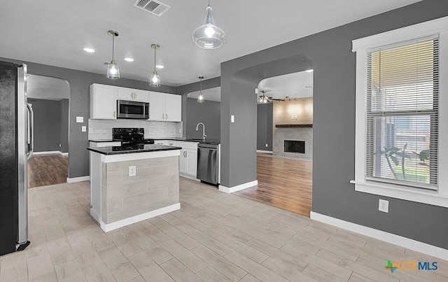 309 Fallen Leaf Ln, Temple, TX 76502 - kitchen featuring appliances with stainless steel finishes, arched walkways, ceiling fan, light wood finished floors, and backsplash
