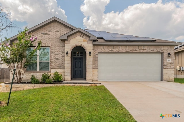 view of front of house with a front lawn, a garage, and solar panels