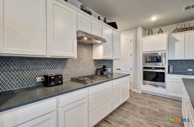 kitchen with white cabinetry, appliances with stainless steel finishes, light hardwood / wood-style floors, and decorative backsplash