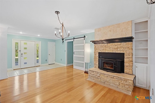 801 Arrowhead Dr, Salado, TX 76571 - unfurnished living room featuring a barn door, a chandelier, wood finished floors, crown molding, and baseboards