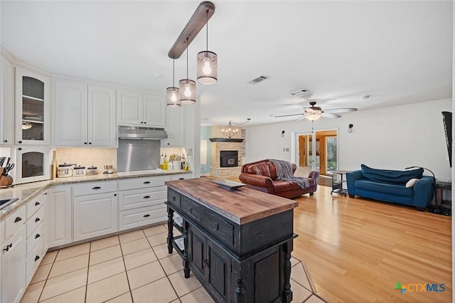 801 Arrowhead Dr, Salado, TX 76571 - kitchen with dark cabinetry, white cabinets, ceiling fan, open floor plan, and under cabinet range hood