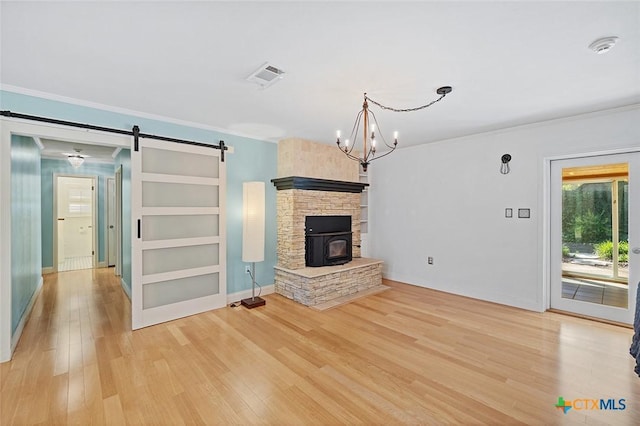 801 Arrowhead Dr, Salado, TX 76571 - unfurnished living room featuring a barn door, light wood-type flooring, crown molding, baseboards, and a chandelier