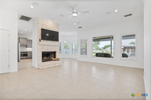 20904 Apache Plum Ln, Pflugerville, TX 78660 - unfurnished living room featuring a ceiling fan, a stone fireplace, light tile patterned floors, and recessed lighting