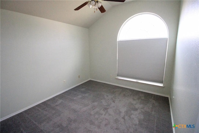 empty room featuring ceiling fan, dark carpet, and vaulted ceiling