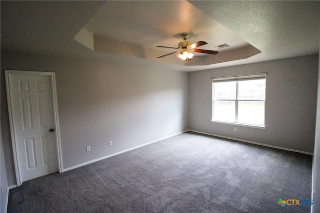 carpeted empty room with a raised ceiling, ceiling fan, and a textured ceiling