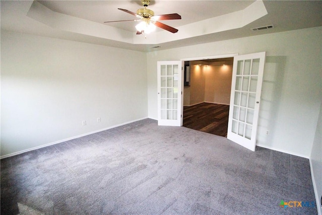 carpeted empty room featuring french doors, a raised ceiling, and ceiling fan