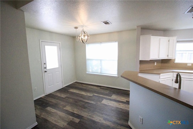 kitchen featuring white cabinets, decorative light fixtures, dark hardwood / wood-style flooring, and a notable chandelier