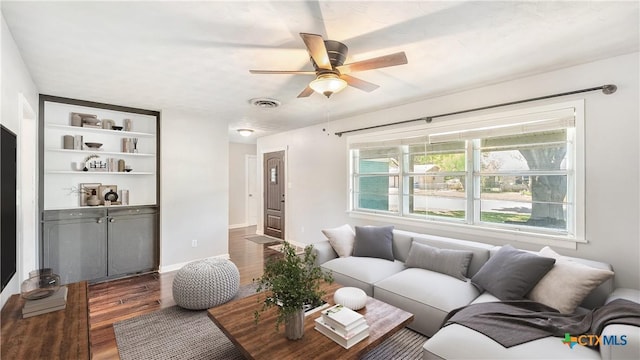 living room featuring ceiling fan, built in features, baseboards, wood finished floors, and visible vents
