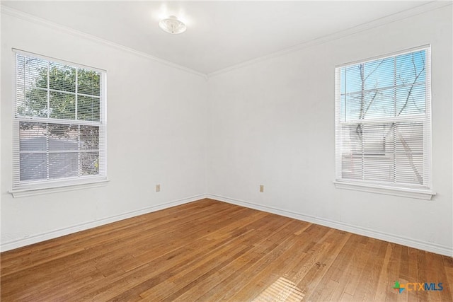 spare room featuring ornamental molding, baseboards, and light wood-style floors