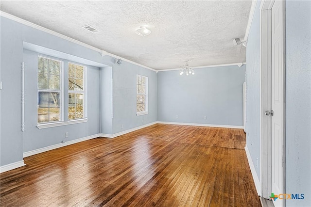 empty room with a chandelier, wood-type flooring, visible vents, and a textured ceiling