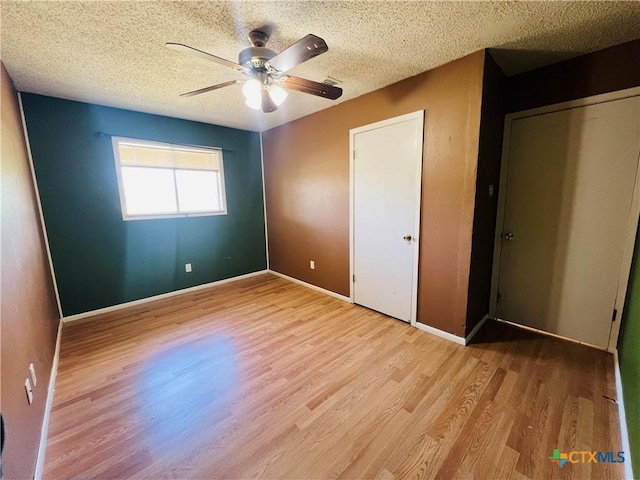 212 Brook St, Seguin, TX 78155 - unfurnished bedroom with wood finished floors, a textured ceiling, a ceiling fan, and a closet