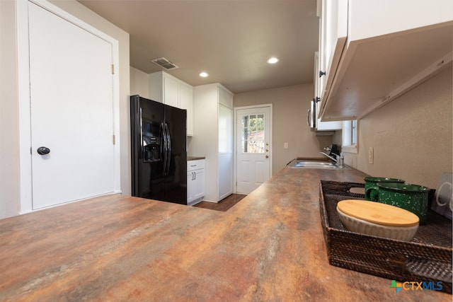 kitchen featuring black refrigerator with ice dispenser, sink, and white cabinets