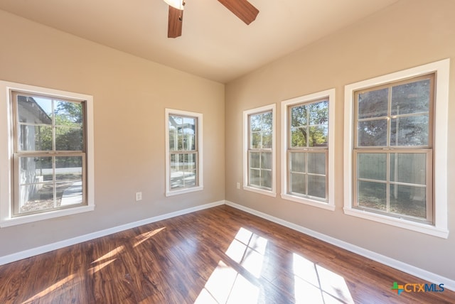 empty room featuring a wealth of natural light, dark hardwood / wood-style flooring, and ceiling fan