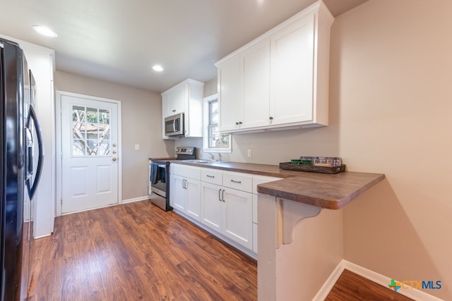 kitchen featuring a kitchen bar, wooden counters, white cabinets, dark hardwood / wood-style flooring, and stainless steel appliances