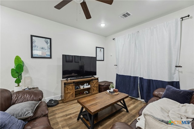 living room featuring ceiling fan, wood finished floors, visible vents, and baseboards