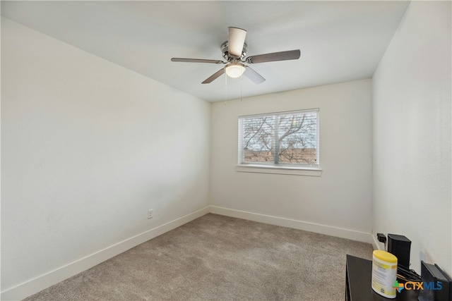 carpeted spare room with a ceiling fan and baseboards