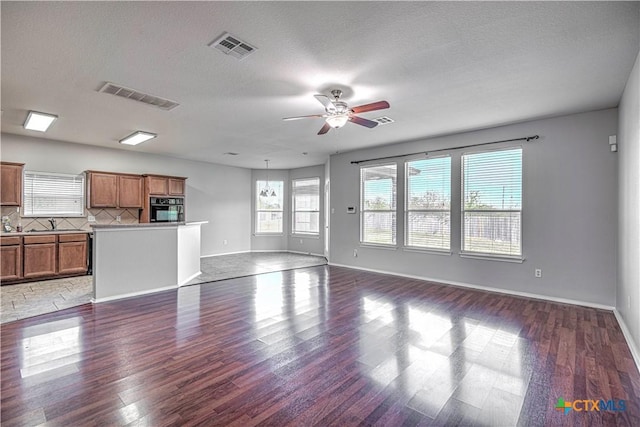 unfurnished living room featuring ceiling fan, dark hardwood / wood-style floors, and a textured ceiling