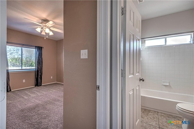 bathroom featuring ceiling fan, a bath, and toilet