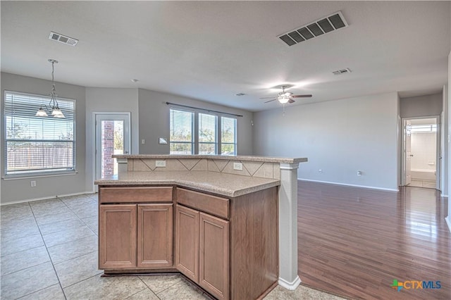 kitchen featuring ceiling fan with notable chandelier, a kitchen island, light tile patterned flooring, and hanging light fixtures