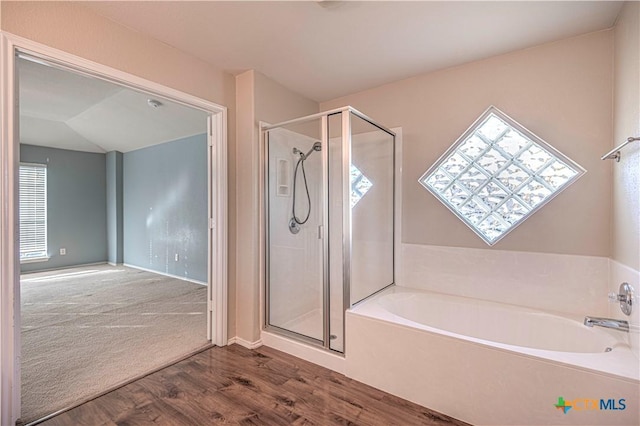 bathroom with a healthy amount of sunlight, wood-type flooring, lofted ceiling, and shower with separate bathtub