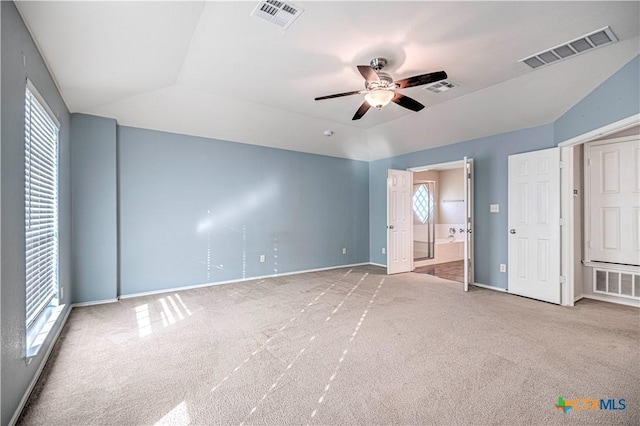 unfurnished bedroom with ensuite bath, ceiling fan, light carpet, and lofted ceiling