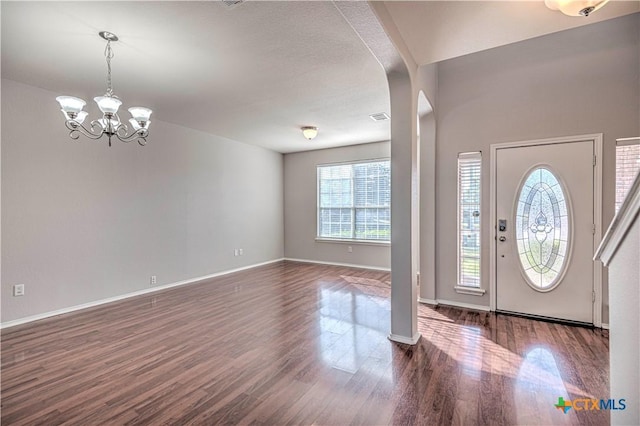 entrance foyer featuring dark hardwood / wood-style flooring, an inviting chandelier, and plenty of natural light