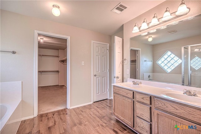 bathroom with vanity, wood-type flooring, and plus walk in shower