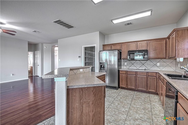 kitchen with a center island, black appliances, sink, decorative backsplash, and ceiling fan