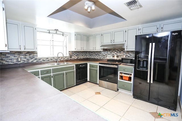 kitchen with under cabinet range hood, backsplash, light tile patterned floors, a sink, and black appliances