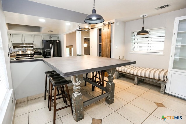 dining space featuring visible vents, recessed lighting, light tile patterned floors, and a barn door