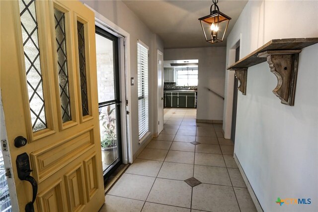 hall featuring baseboards, a sink, and light tile patterned floors