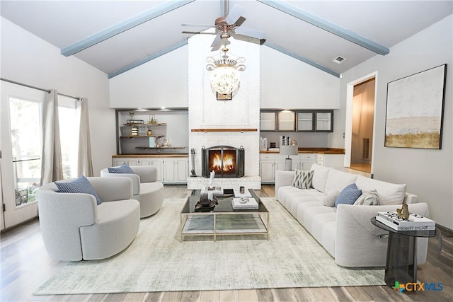 living area with wood finished floors, visible vents, a ceiling fan, and beam ceiling