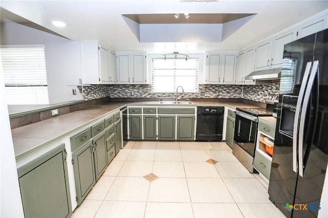 kitchen featuring under cabinet range hood, a sink, black appliances, and tasteful backsplash