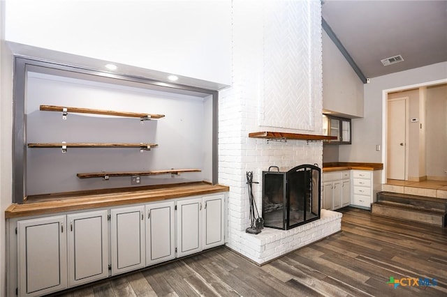 interior space featuring visible vents, recessed lighting, lofted ceiling, a brick fireplace, and dark wood-type flooring