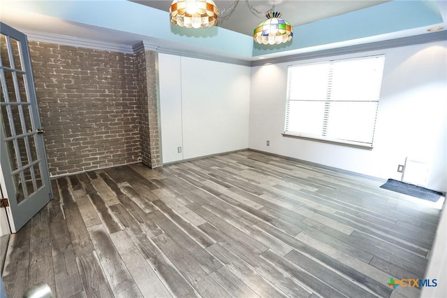 spare room with brick wall and wood finished floors