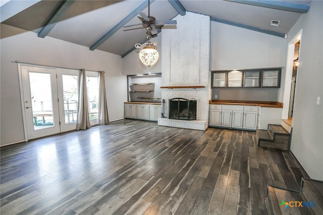 unfurnished living room with high vaulted ceiling, ceiling fan, beamed ceiling, a fireplace, and dark wood-style flooring
