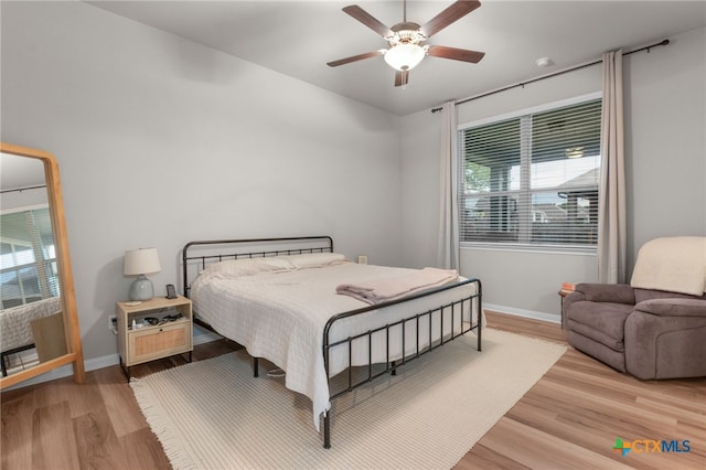 bedroom featuring baseboards, multiple windows, and light wood-style flooring