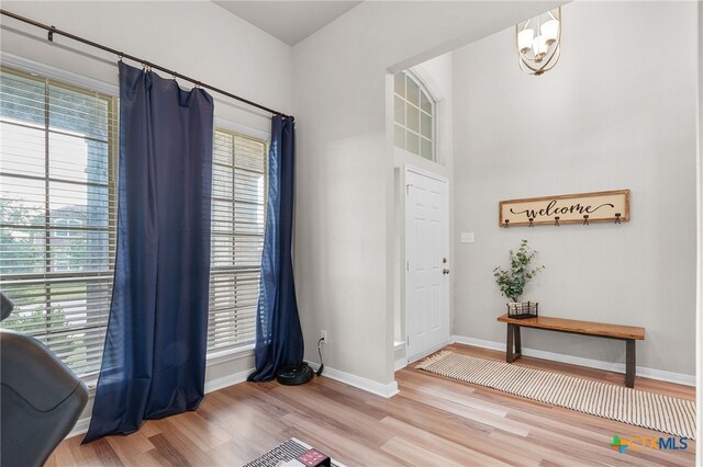 entrance foyer with baseboards, wood finished floors, and a chandelier