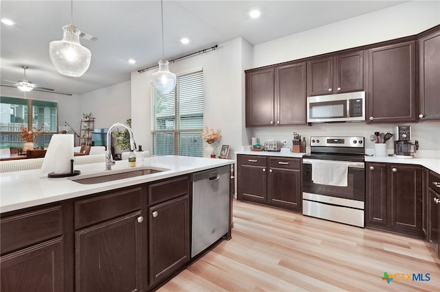 kitchen with dark brown cabinets, a sink, light countertops, stainless steel appliances, and pendant lighting