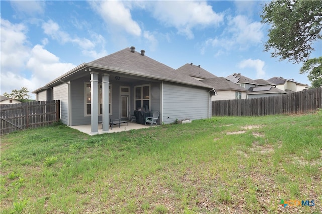 back of property with a patio, a fenced backyard, and a yard