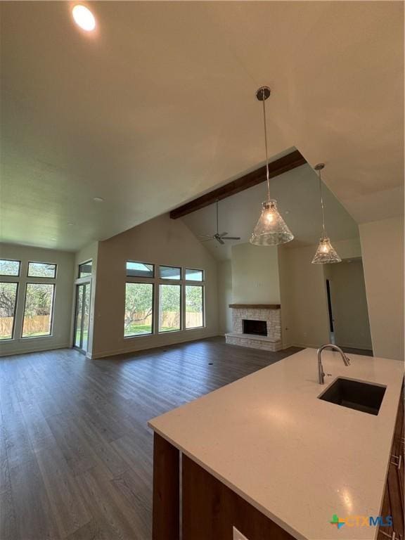 5903 Whippoorwill Rd, Temple, TX 76502 - kitchen with a sink, open floor plan, dark wood-style flooring, a fireplace with raised hearth, and beamed ceiling