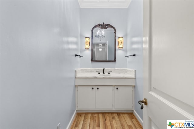 bathroom with vanity, wood-type flooring, and crown molding