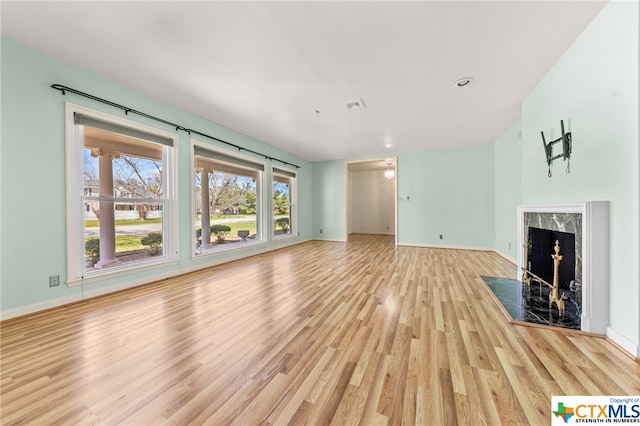 unfurnished living room with a high end fireplace and light wood-type flooring