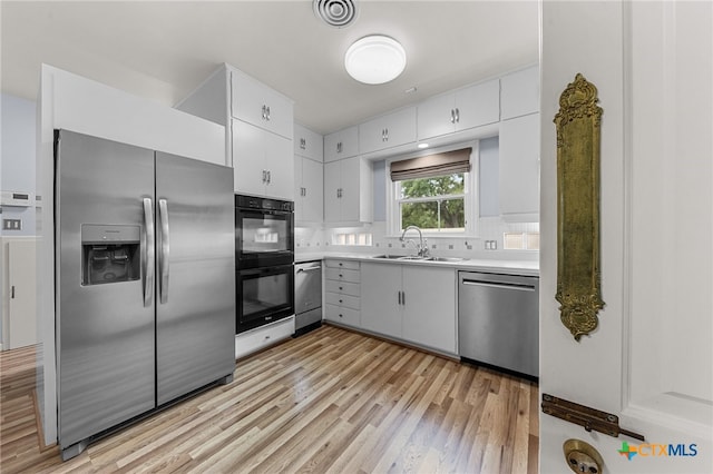 kitchen featuring white cabinetry, sink, light hardwood / wood-style flooring, and appliances with stainless steel finishes