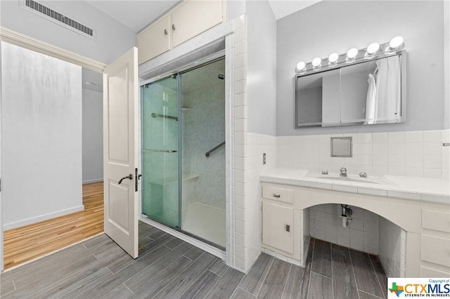 bathroom with sink, hardwood / wood-style floors, and a shower with shower door