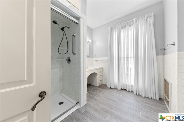 bathroom featuring vanity, a tile shower, and tile walls