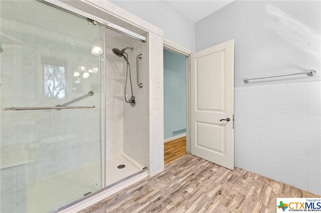 bathroom with walk in shower, tile walls, and wood-type flooring