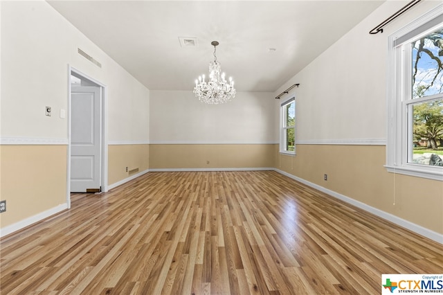 unfurnished room with a chandelier and light hardwood / wood-style flooring