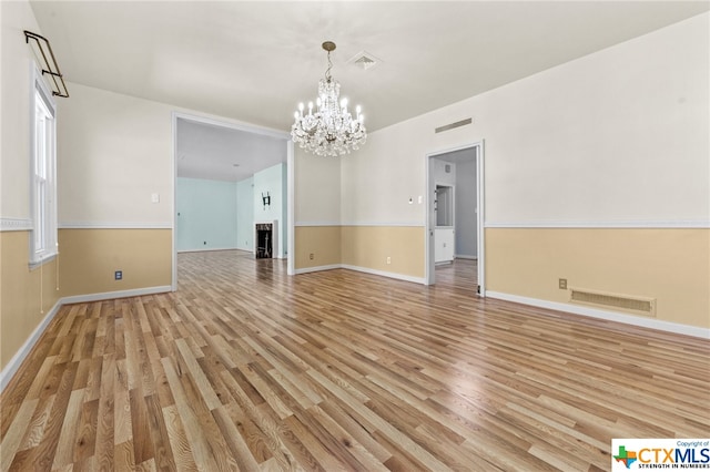 unfurnished room featuring light hardwood / wood-style floors and a notable chandelier